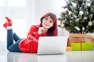 Gülümseyen kadın dizüstü online kat xmas ağacı yanında yatan alışveriş Noel için kullanma