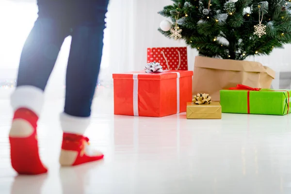 妇女在羊毛袜子去圣诞节礼物箱子在圣诞树之下 — 图库照片