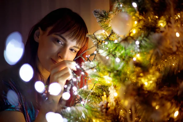 年轻女子和圣诞树充满了灯光装饰 — 图库照片