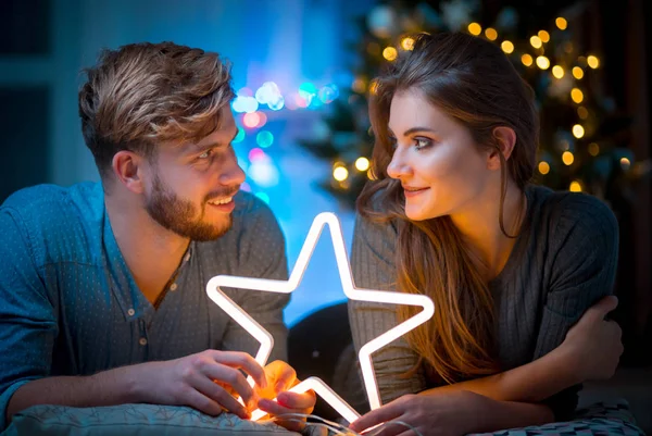 情侣在爱在圣诞节晚上举行发光的白色Led星 舒适的黑暗客厅 — 图库照片