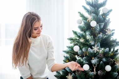 Neşeli kadın parlak beyaz odada Noel ağacı süslemeleri