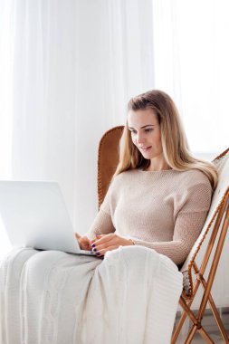 Online çalışma evde rahat koltukta oturan ve, dizüstü bilgisayar kullanarak kadın