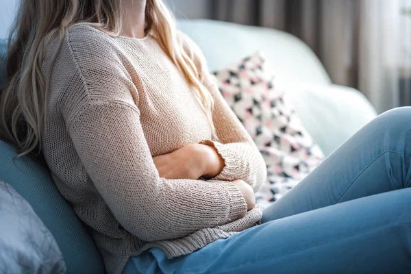 Młoda Kobieta Cierpiąca Ból Brzucha Podczas Siedzenia Kanapie Domu — Zdjęcie stockowe