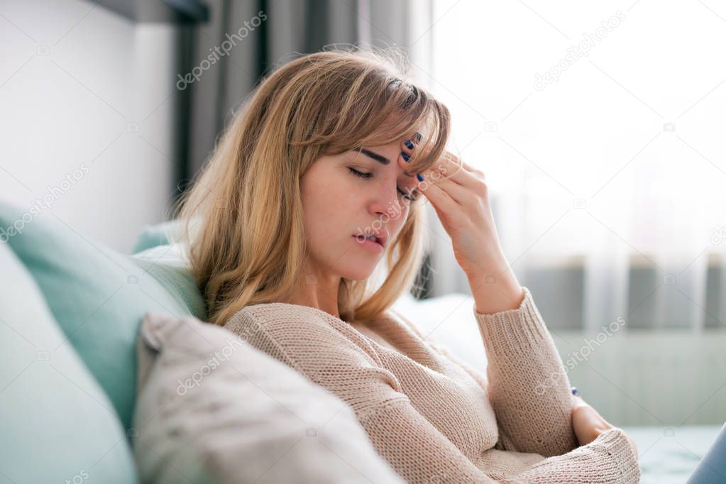 Young woman at home having headache, depressed girl with negative emotions