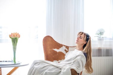 Boş zaman evde, battaniye koltukta aydınlık oturma odası, üzerinde rahatlatıcı ile uyuyan genç kadın