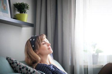 Mutlu genç kadın evde rahatlatıcı, hayal ve hakkında bir şey boş zamanlarında düşünme kanepede oturuyordu