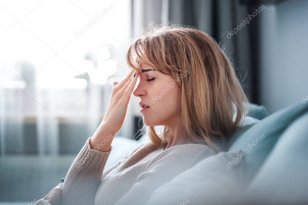 Sad woman sitting on sofa at home, thinking about important things