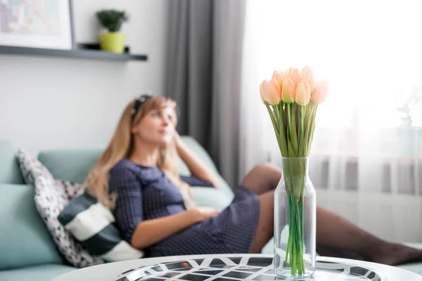 Свіжі Пінцетні Тюльпани Столі Вдома Молода Жінка Розслабляється Дивані Розмитому — стокове фото