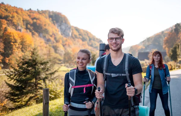 真正的朋友团体在旅游之旅中带着背包和徒步棒行走 — 图库照片