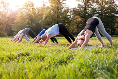 Parkta dışarıda yoga yapan insanların karışık yaş grubu