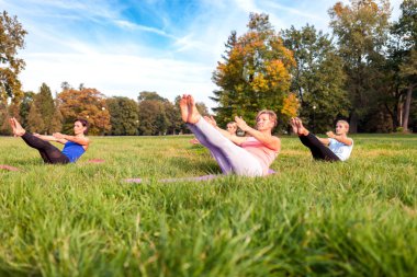 Parkta dışarıda yoga yapan insanların karışık yaş grubu
