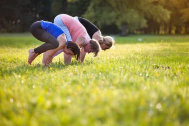 Parkta yoga, bakasana turna pozu veren bir grup karışık yaş kadını.