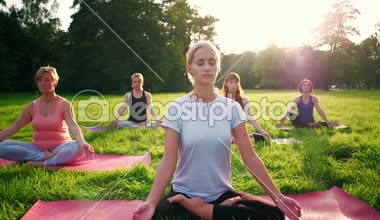 Parkta yoga yapan ve gün batımında meditasyon yapan bir grup karışık yaş kadını.