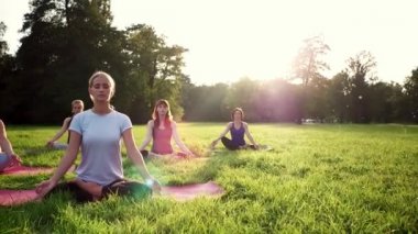 Parkta yoga yapan ve gün batımında meditasyon yapan bir grup karışık yaş kadını.