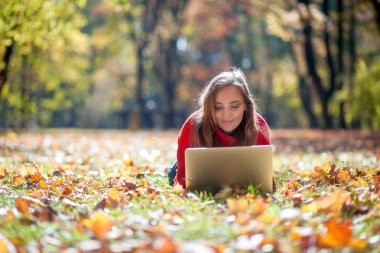 Güzel gülümseyen kadın dizüstü çim üzerinde yalan açık kullanma