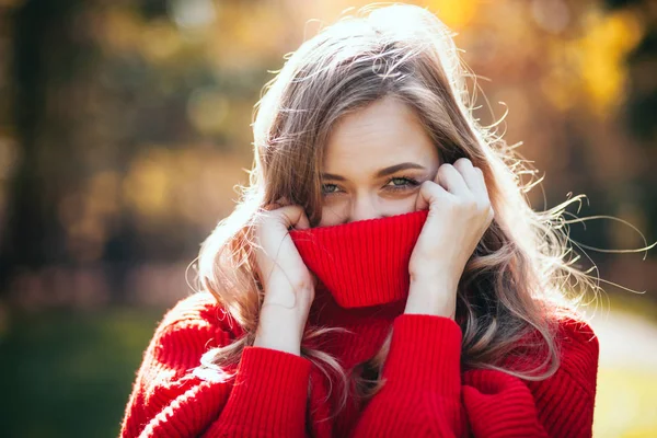 Natural young woman in soft warm knitted sweater walking outdoors, autumn and spring