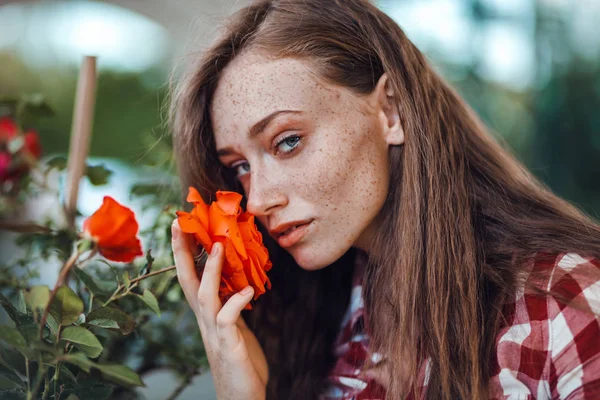 美丽的雀斑女人在格子衬衫嗅到玫瑰的花 园艺概念 — 图库照片
