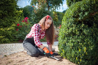 Bahçesinde bahçeyle uğraşan genç bir kadın.