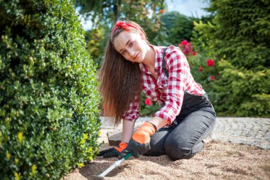 Bahçesinde bahçeyle uğraşan genç bir kadın.