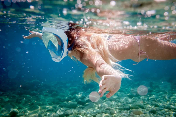 Woman snorkeling with full face mask in the tropical sea