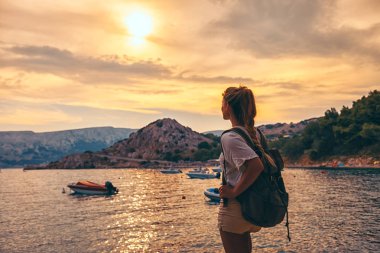 Defne deniz yukarıda gün batımında seyir sırt çantası kadınla gezgin