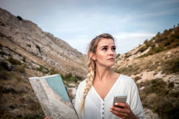 Hiker woman on hiker trail looking at map and smartphone, travel and active lifestyle concept