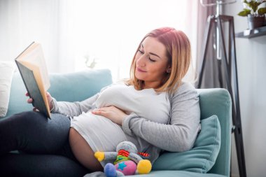 Hamile kadın koltuk okuma kitabı göbek bakarak rahatlatıcı