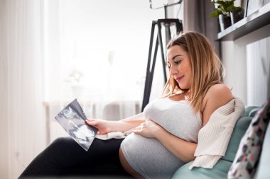 Hamile kadın kanepede onu bebek görünümlü ultrason görüntü, USG fotoğraf