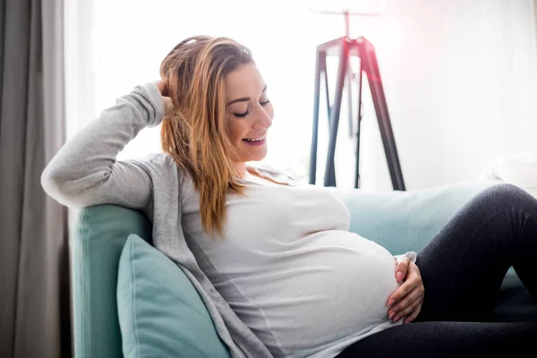 Femme enceinte se détendre à la maison sur le canapé — Photo