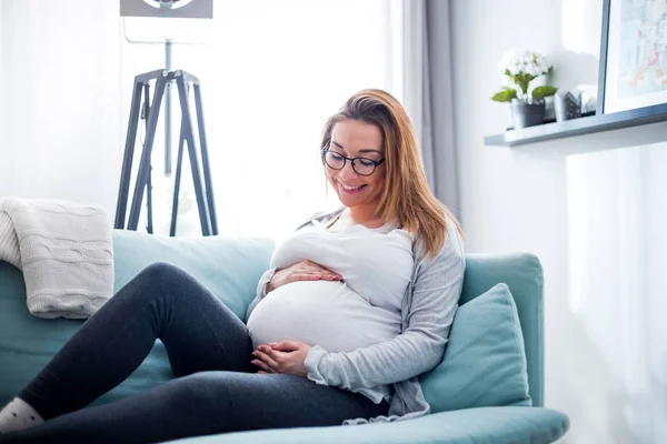 Terhes nő otthon a kanapén pihen — Stock Fotó
