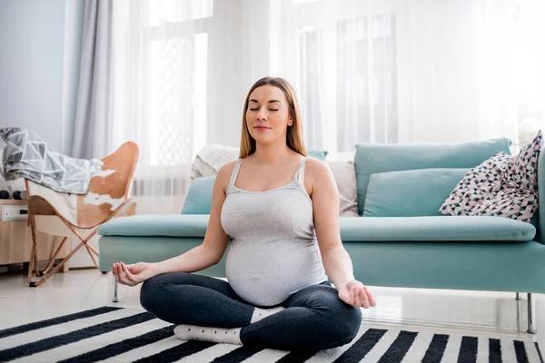 Méditer sur la maternité, femme enceinte méditer assis sur le tapis à la maison — Photo