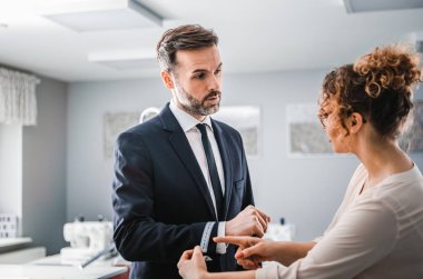 Atölyede dikiş elbisesi için istemciyi ölçmek için bant kullanan terzi