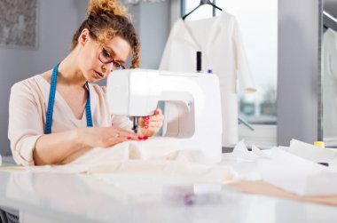 Terzi dikiş makinesi kullanarak iş sırasında, atölyede moda tasarımcısı