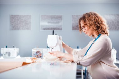 Terzi dikiş makinesi kullanarak iş sırasında, atölyede moda tasarımcısı