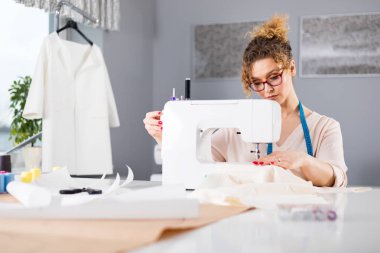 Terzi dikiş makinesi kullanarak iş sırasında, atölyede moda tasarımcısı