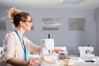 Terzi dikiş makinesi kullanarak iş sırasında, atölyede moda tasarımcısı