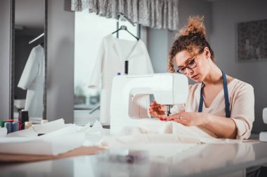 Terzi dikiş makinesi kullanarak iş sırasında, atölyede moda tasarımcısı