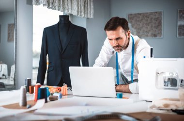 Atölyede dizüstü bilgisayar, modern moda tasarımcısı kullanarak iş sırasında Terzi