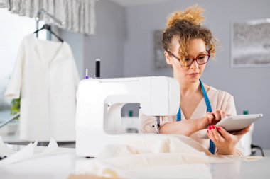 Dijital tablet kullanarak iş sırasında Terzi, atölyede modern moda tasarımcısı