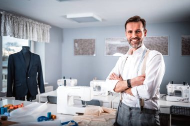 Gülümseyen terzi dükkanı sahibi atölye masası, moda tasarım iş üzerinde duran