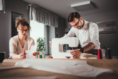 Moda tasarım stüdyosunda dikiş makinesi kullanarak proje çalışmaları sırasında profesyonel terziler