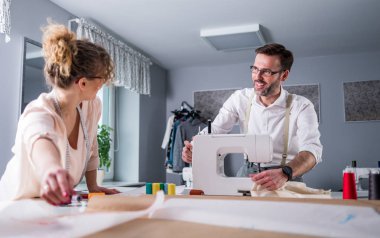 Moda tasarım stüdyosunda dikiş makinesi kullanarak proje çalışmaları sırasında profesyonel terziler