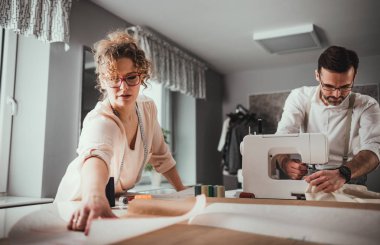 Moda tasarım stüdyosunda dikiş makinesi kullanarak proje çalışmaları sırasında profesyonel terziler