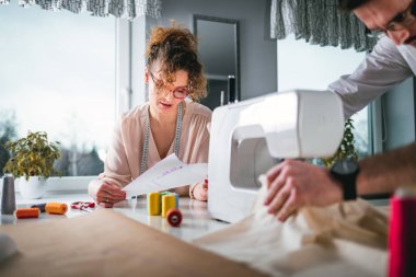 Moda tasarım stüdyosunda dikiş makinesi kullanarak proje çalışmaları sırasında profesyonel terziler