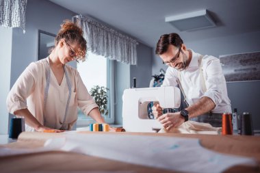 Moda tasarım stüdyosunda dikiş makinesi kullanarak proje çalışmaları sırasında profesyonel terziler