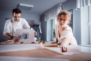 Moda tasarım stüdyosunda dikiş makinesi kullanarak proje çalışmaları sırasında profesyonel terziler