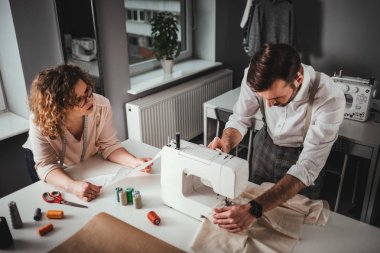 Moda tasarım stüdyosunda dikiş makinesi kullanarak proje çalışmaları sırasında profesyonel terziler