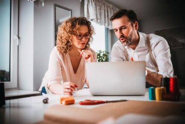 Moda tasarım stüdyosunda dizüstü bilgisayar kullanarak proje çalışmaları sırasında profesyonel terziler