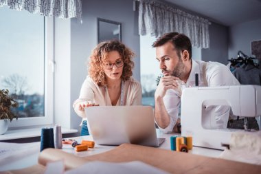 Moda tasarım stüdyosunda dizüstü bilgisayar kullanarak proje çalışmaları sırasında profesyonel terziler