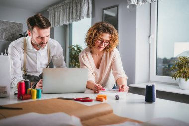 Moda tasarım stüdyosunda dizüstü bilgisayar kullanarak proje çalışmaları sırasında profesyonel terziler